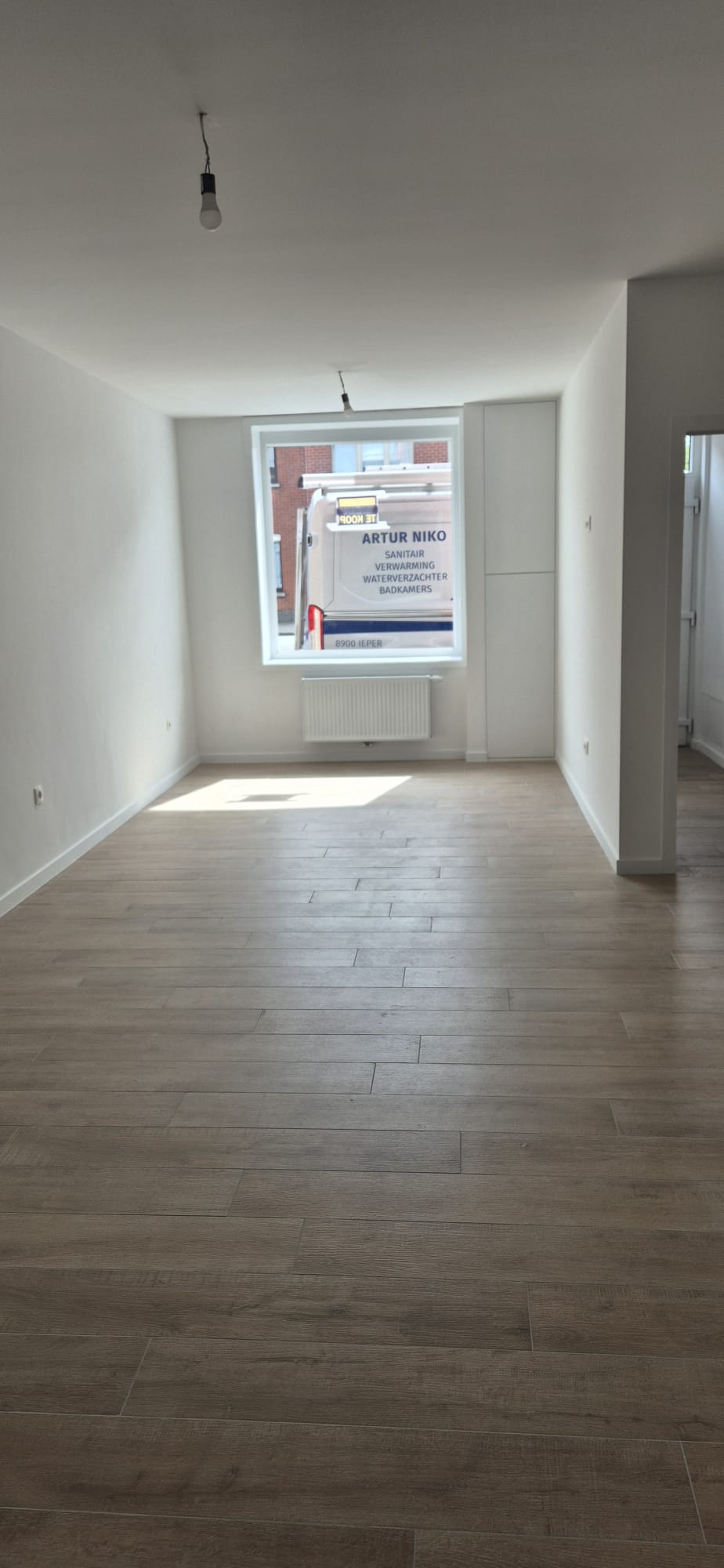 Volledig gerenoveerde leefruimte met grote houtlook tegelvloer en nieuwe radiator — Artur Niko Ieper